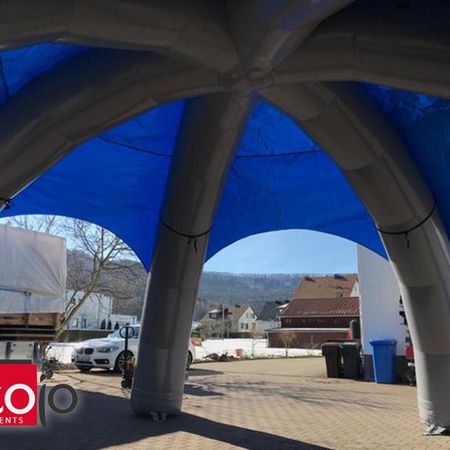 Großes, offenes, aufblasbares Eventzelt mit mehreren Bögen, das als Wetterschutz über einem Veranstaltungsbereich dient.