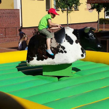 Junge Person beim Reiten auf einem Rodeo-Bullen während einer Veranstaltung im Freien.