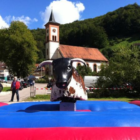 Mechanisches Bullriding vor Kirche und Hügelkulisse bei Tageslicht