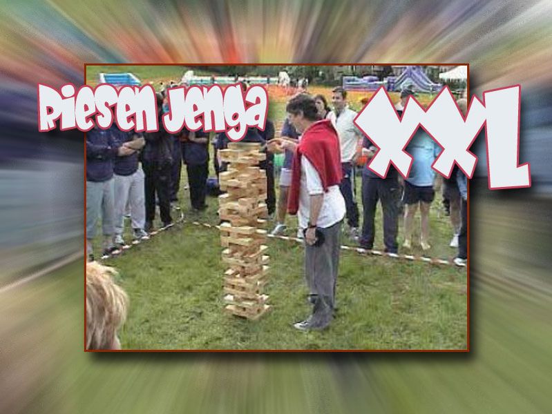 Ein Mensch zieht einen Holzblock aus dem XXL Jenga Spiel