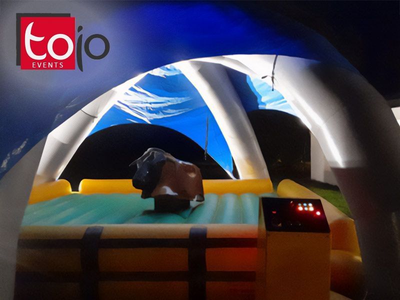 Mechanisches Bullriding unter beleuchtetem Eventzelt bei Nacht